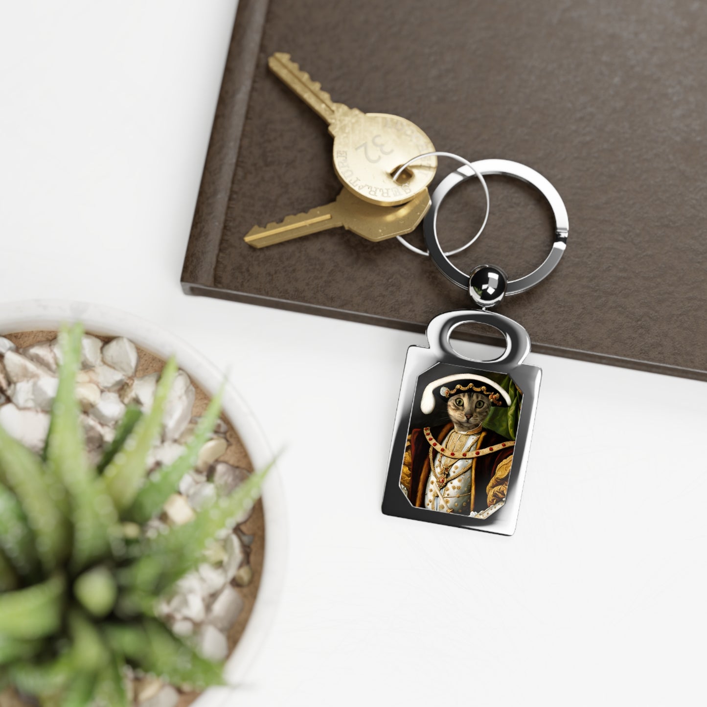 Keychain with a portrait charm on a surface with a key and plant.