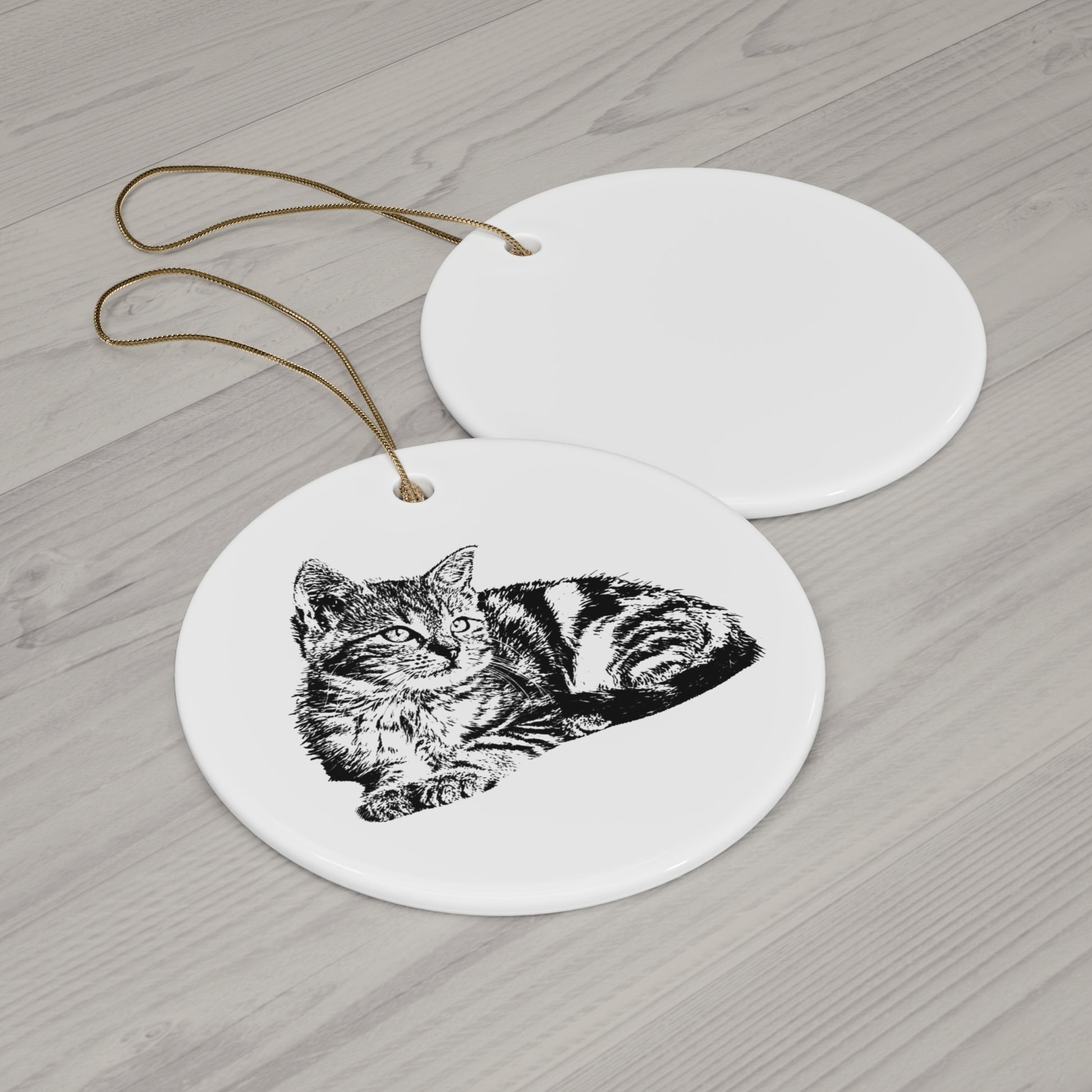 Round ceramic ornament with a black and white cat illustration on a wooden surface