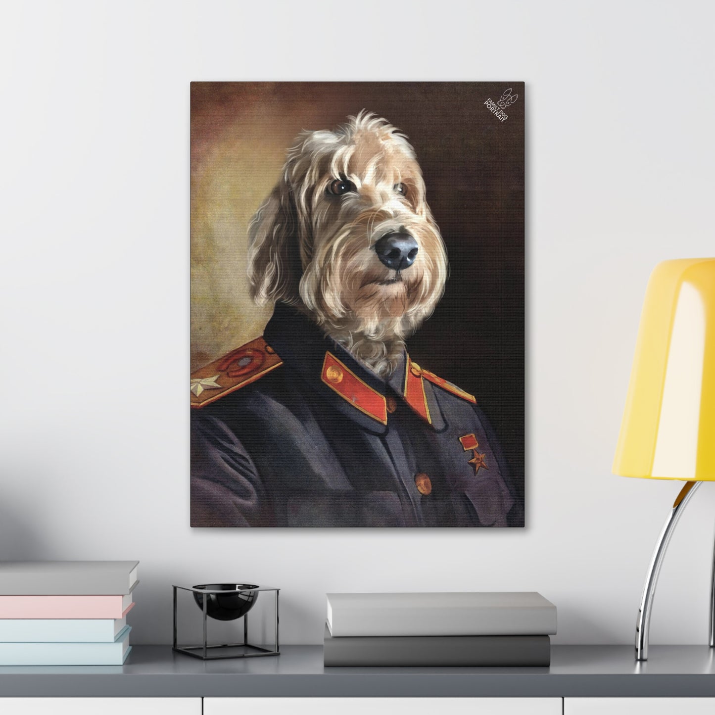 Framed portrait of a dog in military attire on a wall above a desk with books and a lamp.