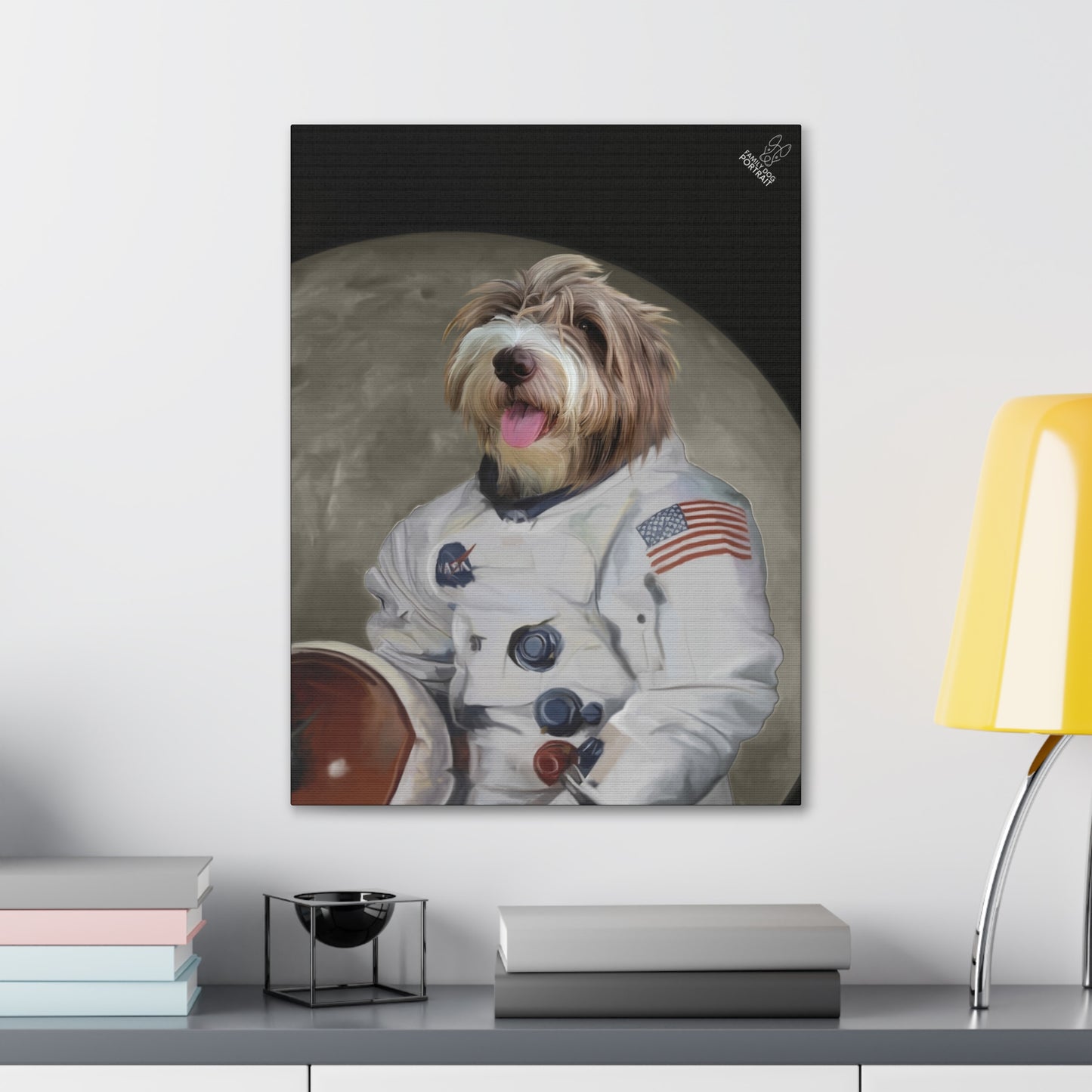 Framed artwork of a dog in an astronaut suit with a moon background on a wall above a desk.
