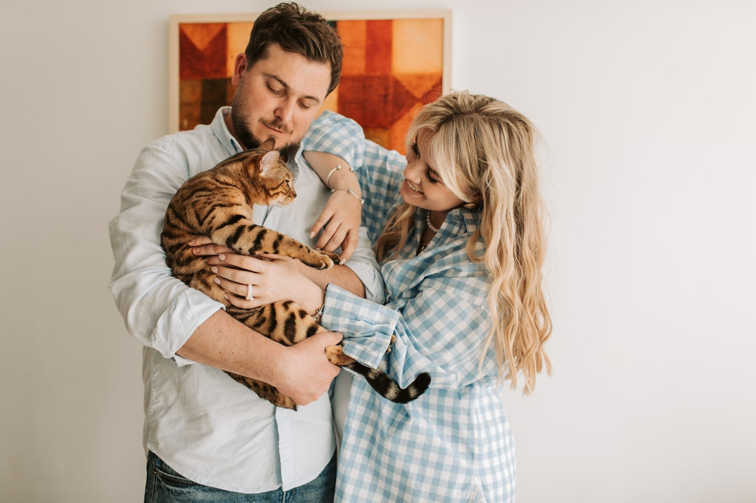 Cat held by man. Both couples are looking at the cat with care. 
