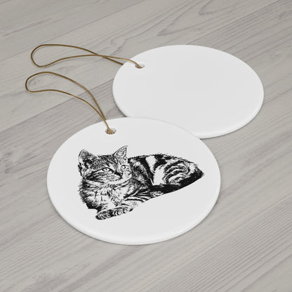 Round ceramic ornament with a black and white cat illustration on a wooden surface