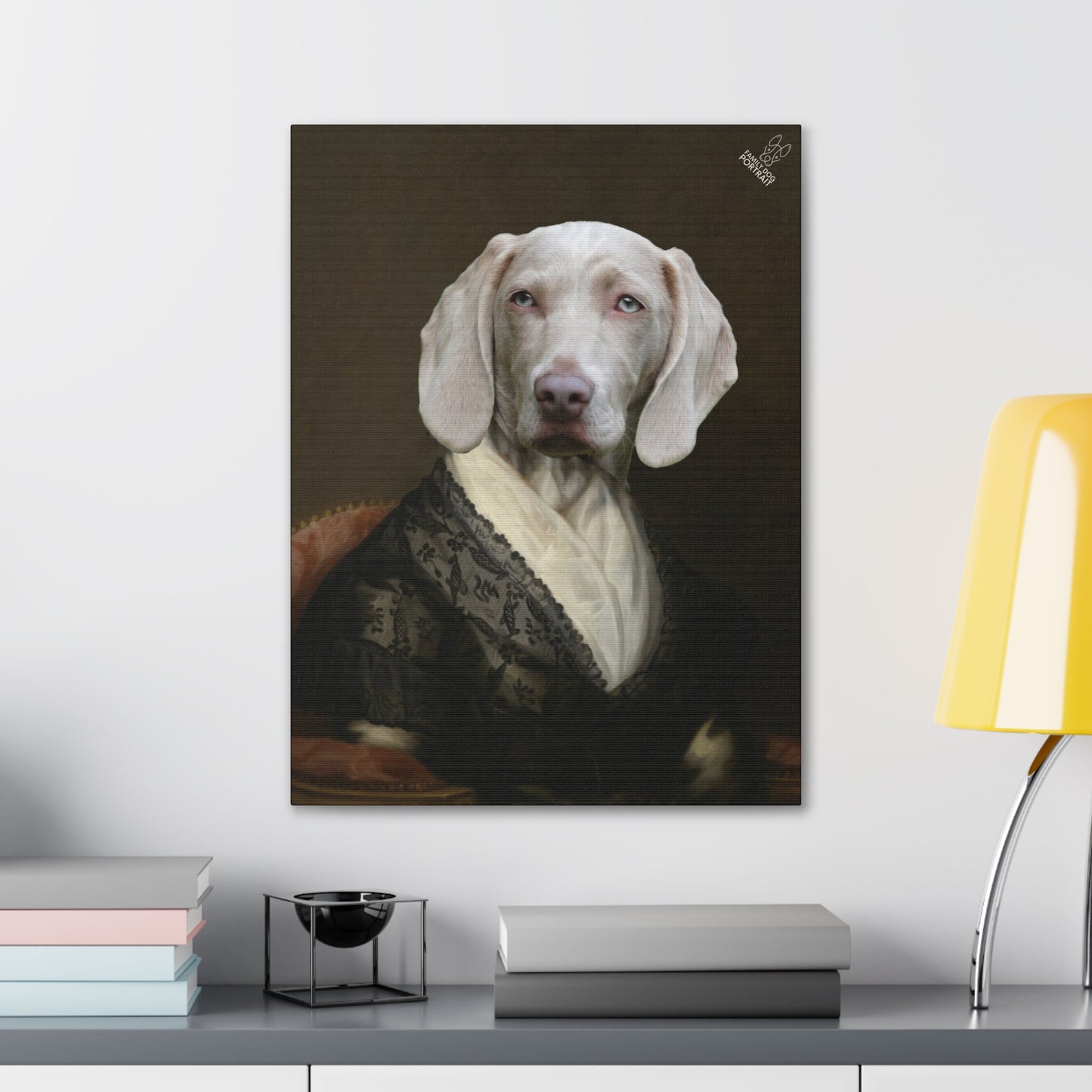 Framed portrait of a dog on a wall above a desk with books and a lamp.