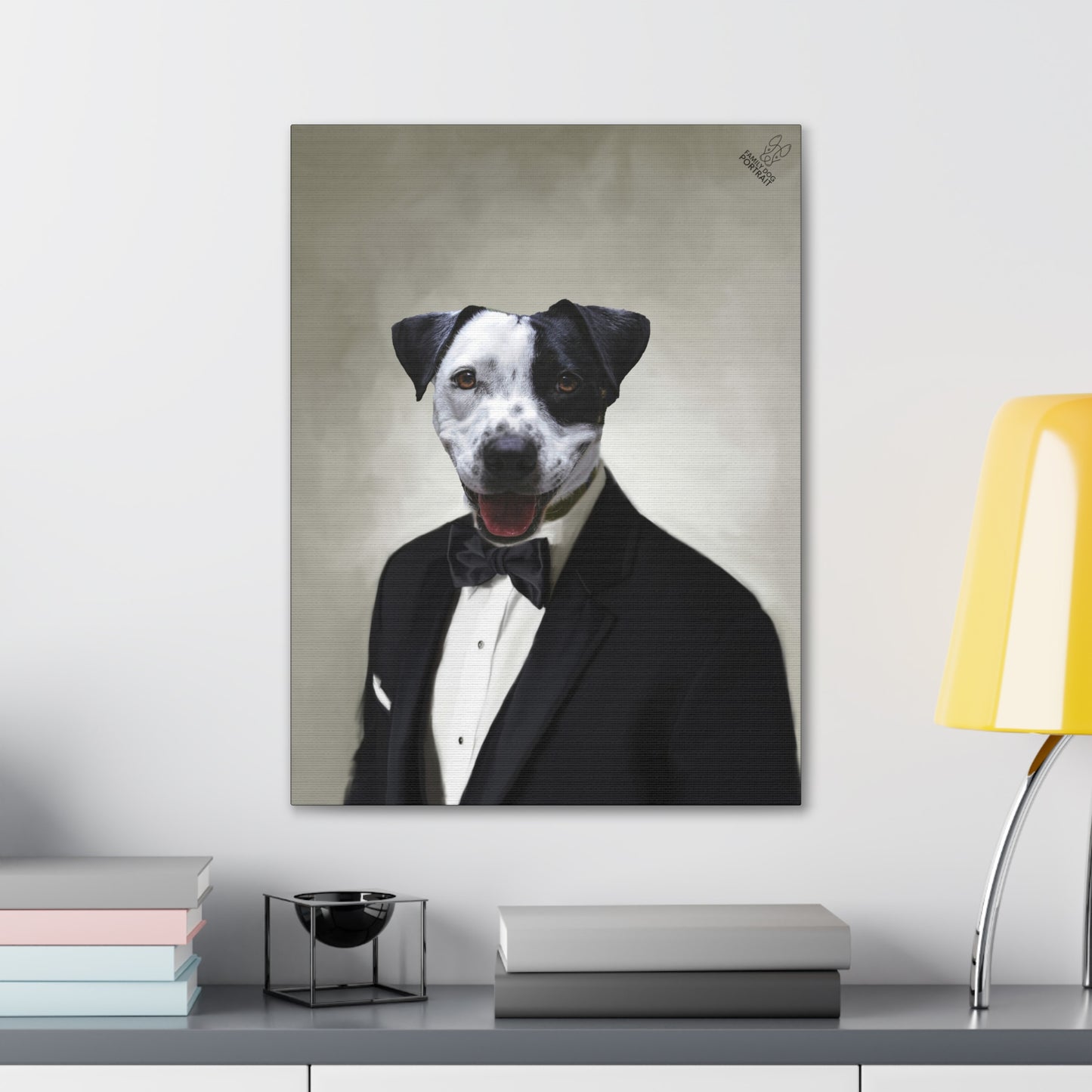 Canvas print of a dog in a tuxedo on a wall above a desk with books and a lamp.